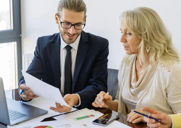 Two business professionals reviewing financial documents and graphs during a meeting.