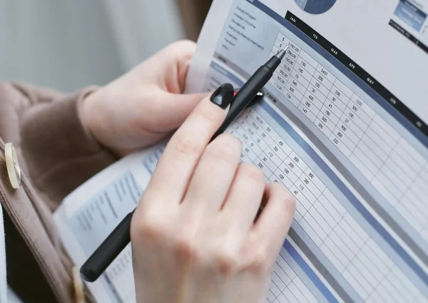 Hands holding a pen review a family budget document with graphs and tables.